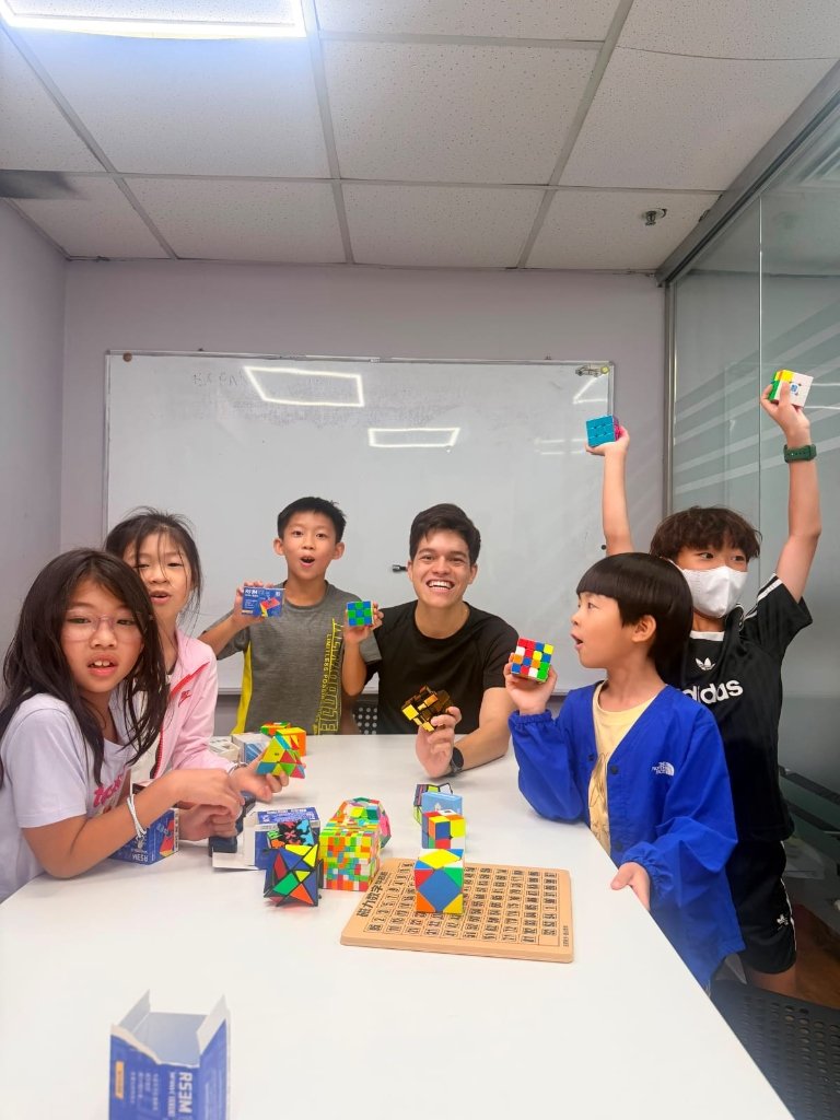 Joseph Jimenez teaching young cubing students holding their solved cubes