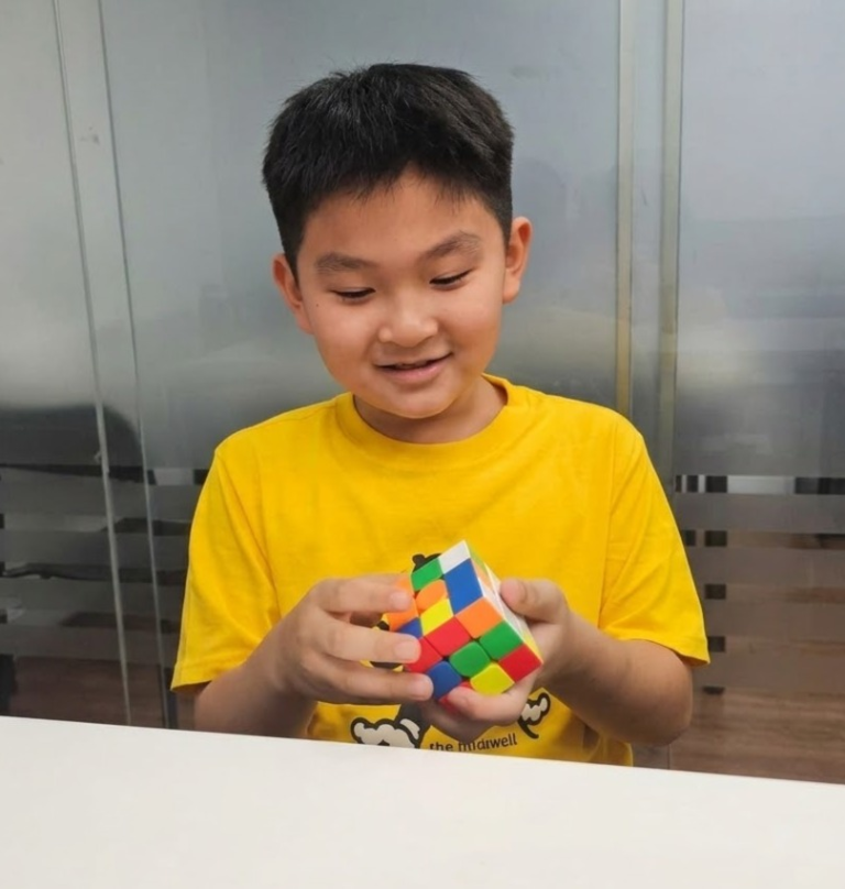 Young student in a yellow shirt solving a twisty puzzle